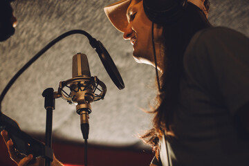Singer recording song in professional studio with microphone and headphones