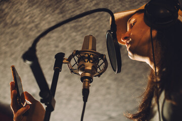 Singer recording song using smartphone app in music studio