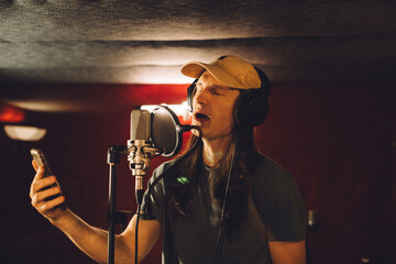 Singer recording song in professional studio using smartphone