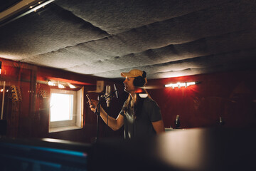Singer recording song in professional studio with microphone and phone
