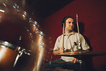 Drummer recording music in professional studio with headphones and drumsticks