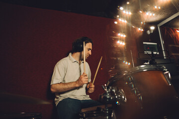 Drummer playing drums in recording studio with headphones
