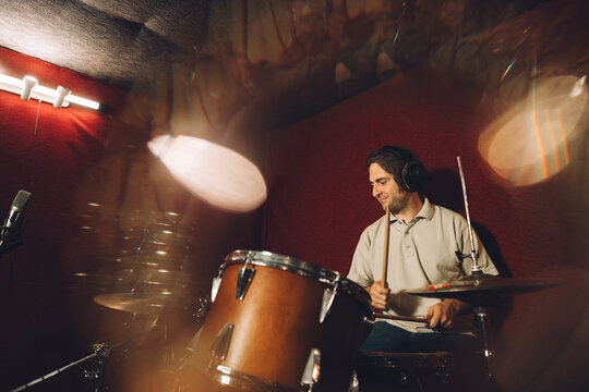 Drummer recording music in professional studio with headphones - Powered by Adobe