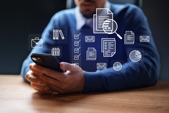 Professional man using smartphone to manage tasks and documents in a modern office environment at evening - Powered by Adobe