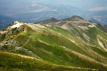 Scenic view of rolling green hills and rugged terrain.