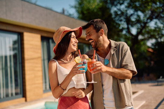 Happy couple toasting while cocktails and having fun during summer.