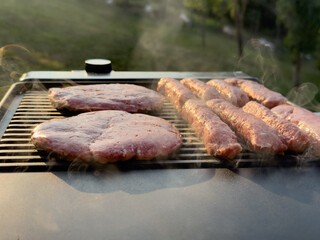Grilling delicious marinated steaks and burgers on a barbecue grill, with smoke rising and a lush...