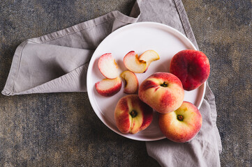 Close up of whole and sliced peaches and a knife are placed on a plate on the table top view