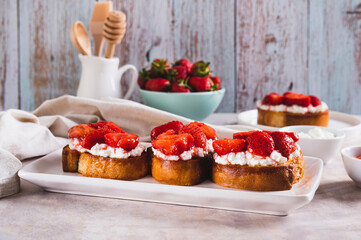 Appetizing bruschetta with ricotta and stewed strawberries on a plate on the table