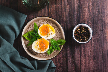 Soft-boiled egg split in half with spices and basil leaves on a plate on a table top view