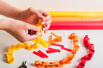 A girl's hands fold a strip of paper to make a paper chain