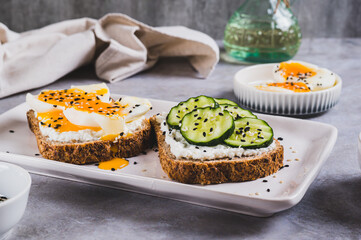 Open sandwiches with ricotta, cucumber and soft-boiled egg on a plate on a table