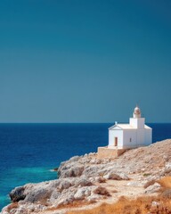 White lighthouse on rocky cliff overlooking blue ocean under clear sky