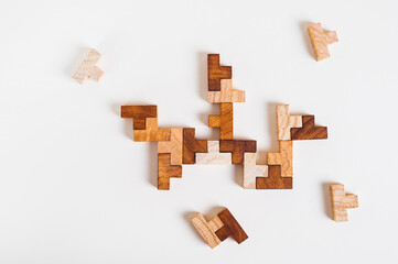 Wooden puzzle pieces stacked together on a light background top view