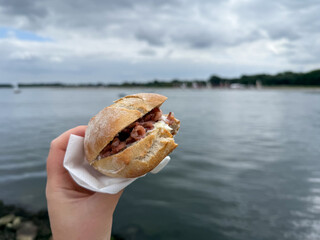 Traditional north german street food wheat bun with north sea shrimps Nordseekrabben in the hand close up in Luebeck Travemuende