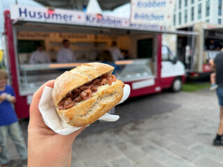 Traditional north german street food wheat bun with north sea shrimps Nordseekrabben in the hand close up in Luebeck Travemuende
