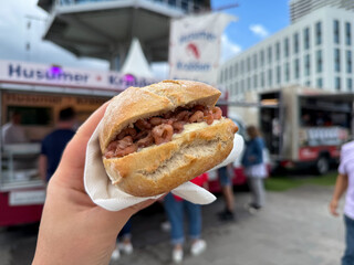 Traditional north german street food wheat bun with north sea shrimps Nordseekrabben in the hand close up in Luebeck Travemuende