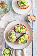 Homemade toasts with cod liver, cucumber and herbs on a plate on a table top and vertical view