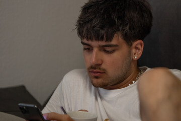young man with mobile phone or smartphone at home on the sofa