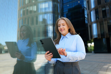 Professional woman interacts with tablet in modern cityscape during bright daylight