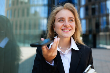 Smiling professional woman speaks into her phone outside modern office building