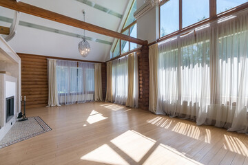 A spacious living room with large windows providing natural light and wooden trim elements. The...