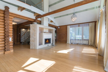 A spacious living room with wooden beams and a large fireplace, illuminated by natural 
light, with...