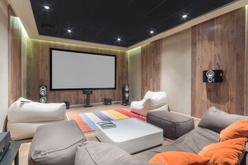 The stylish interior of a home theater with comfortable upholstered chairs, a large screen and a...