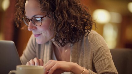 Woman with Glasses Smiling while Using Laptop in Cozy Indoor Setting