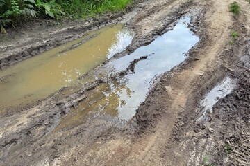 The dirt road is filled with muddy puddles after a rain. Concept of off-road.