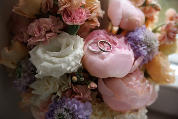 Elegant floral arrangement featuring pastel roses and other flowers with wedding rings placed gently on the petals, symbolizing love and commitment in a beautiful, serene setting.