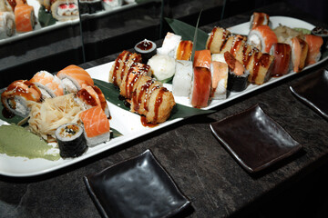 Delicious assortment of sushi featuring various rolls with sushi rice, fish, and toppings. The elegant platter is complemented by soy sauce, ginger, and wasabi, ready for serving.