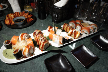 Delicious assortment of sushi featuring various rolls with sushi rice, fish, and toppings. The elegant platter is complemented by soy sauce, ginger, and wasabi, ready for serving.