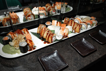 Delicious assortment of sushi featuring various rolls with sushi rice, fish, and toppings. The elegant platter is complemented by soy sauce, ginger, and wasabi, ready for serving.