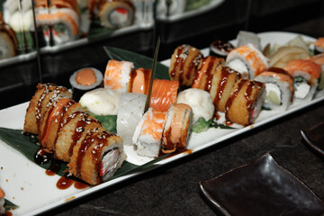 Delicious assortment of sushi featuring various rolls with sushi rice, fish, and toppings. The elegant platter is complemented by soy sauce, ginger, and wasabi, ready for serving.