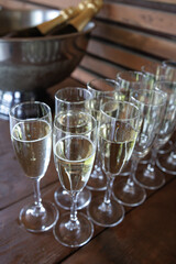 Champagne glasses neatly arranged, ready for a celebration. A bottle sits in a cooler, indicating preparation for a festive occasion or toast. Bubbly, elegant, and inviting.