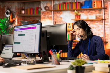 Call center agent tracking shipments at work, looking at computer screen, handling delivery delays....