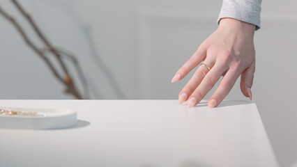 Elegant almond nails with beige gel polish, close-up of glamorous feminine hands in soft light.