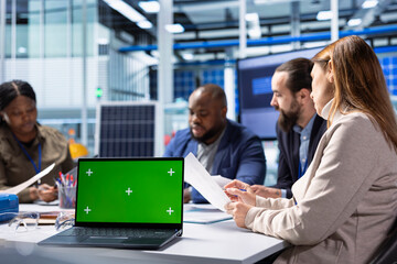 Naklejka premium Industrial plant coworkers identifying technical bottlenecks using chroma key notebook. Teamworking businesspeople in factory office analyzing data, reviewing system health metrics with mockup laptop