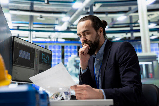 Male factory employee reviewing maintenance and systems in a solar panel plant, ensuring equipment functionality and contributing to reliable, sustainable industrial operations.