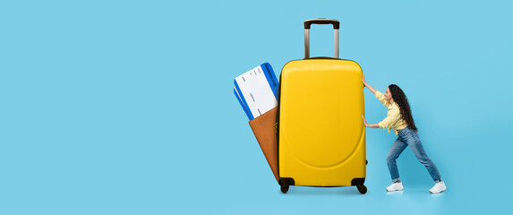 A traveler prepares for vacation during summer, pushing a vibrant yellow suitcase filled with...