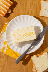 butter creative block with lettering "butter" on white plate and bread around.white background top view and copy space. stylish advertising or poster for butter brand 