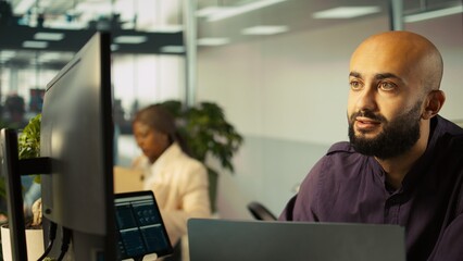 Smiling employee in warm office working on company project, multitasking. Cheerful freelancer...