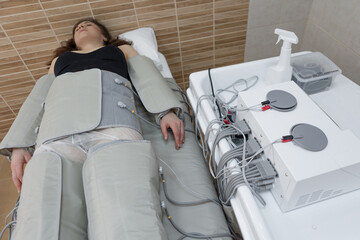 Woman in wellness center, undergoing pressotherapy for lymphatic system stimulation