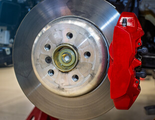 Car ventilated front brake disc with red caliper. Modern brake disc with ventilation holes and...