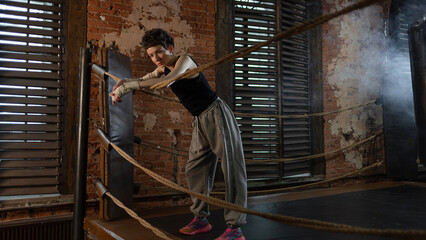Boxer woman taking break on ropes, intense cinematic training session pause