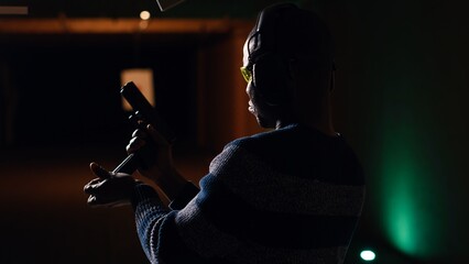 Man reloading handgun in indoor shooting range next to friends firing at targets. Person loading...
