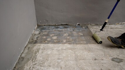 Professional construction worker carefully spreading primer across concrete surface, ensuring thorough waterproofing preparation for structural protection and maintenance