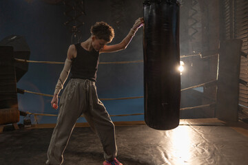 Boxing with a punching bag, sports achievements concept, female wrestler in a boxing ring, cinematic image, mood, motivating stories