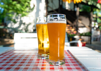 Two tall glasses of cold beer sparkling attractively in sunlight at a summer cafe